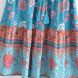 Detail of bohemian floral print dress with tassel drawstring and layered hem design