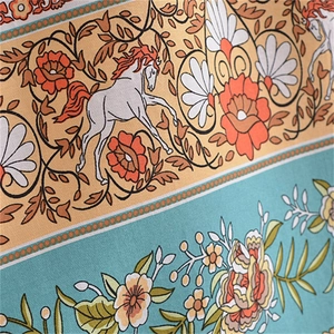 Gros plan sur tissu bohème aux motifs de fleurs orange et chevaux blancs élégants