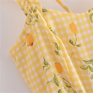 Détail du tissu vichy jaune avec imprimé citron et bretelles volantées sur la robe d'été