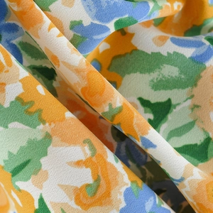 Close-up detail of soft floral fabric with orange and blue abstract patterns and textures