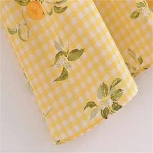 Vue détaillée du tissu à carreaux jaunes avec imprimé orange et coutures soignées