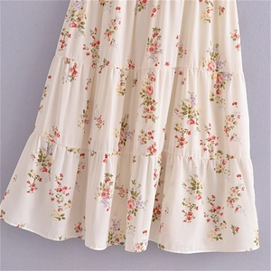 Détail de robe fleurie à volants montrant de délicates fleurs rouges et jaunes sur tissu crème