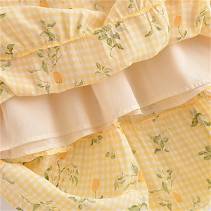 Détail du tissu vichy jaune avec imprimé citron et design à volants multicouches