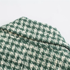 Detail of green and white tweed plaid lapel showing textured fabric weaving and stitch quality