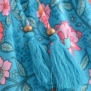 Detail of bohemian V-neck dress showing blue tassels and floral print fabric