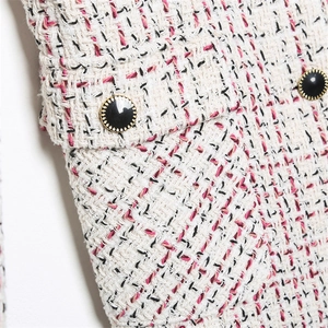 Close-up of tweed jacket texture with golden edged buttons and flap pocket detail