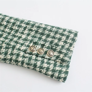 Detail of tweed blazer cuff with green pattern and vintage lion embossed gold buttons