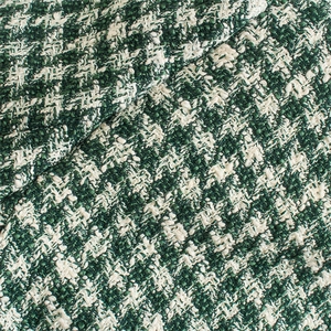 Close-up of green and white tweed fabric with textured double-breasted suit jacket weave