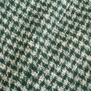 Detailed macro view of green and white houndstooth tweed texture on a slim suit jacket