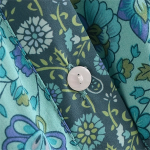Macro shot of white button and floral print on woven fabric placket of long dress