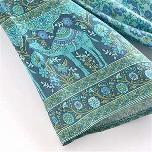 Detail shot of bohemian dress fabric with cyan camel print and floral patterns
