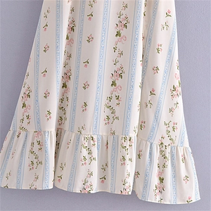 Détail de l'imprimé fleuri sur tissu blanc avec rayures en dentelle bleue et volants