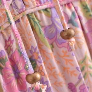 Detail of floral V-neck dress featuring adjustable drawstring with bronze bead accents