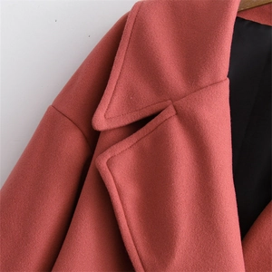Detailed close-up of coral pink wool coat showing lapel stitching and thick textured fabric