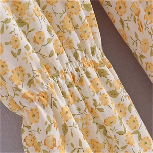 Close-up detail of floral chiffon dress showing smocking technique and yellow flower print