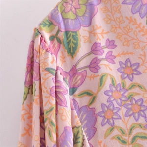 Close-up of floral print and pleated detail on women's V-neck tassel dress fabric