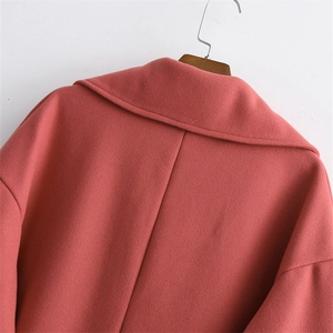 Detailed view of the notch lapel and fine wool blend texture on a coral coat