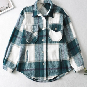 Detail of plaid shacket featuring flap chest pockets and metal buttons on flannel fabric