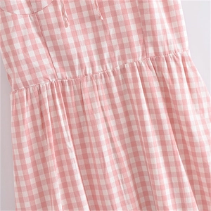 Détail d'une robe vichy rose et blanche avec taille haute plissée et texture de coton doux