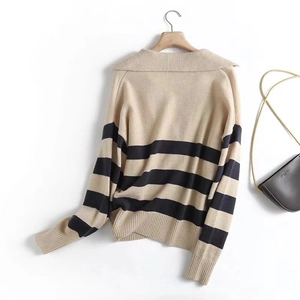 Close-up of beige and black striped knit polo sweater with ribbed cuffs and collar