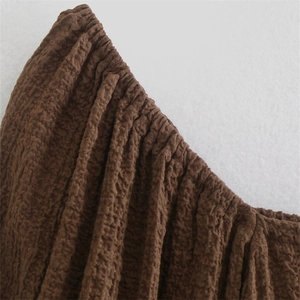 Close-up of brown textured crepe fabric with elastic pleated edge on slim fit bodysuit