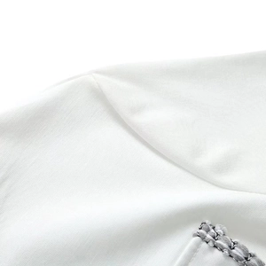 Close-up of white knit T-shirt featuring tweed pocket trim and textured fabric detail