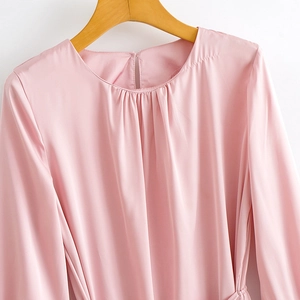 Pink long sleeve satin dress featuring pleated crew neck and silky texture on a wooden hanger