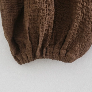 Detailed macro view of dark brown seersucker fabric texture and elastic cuff finish