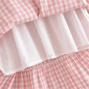 Détail de l'ourlet de robe à carreaux rose avec doublure à volants blancs