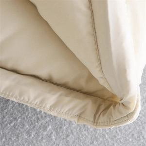 Detail shot of cream quilted vest showing smooth fabric texture and precise stitching