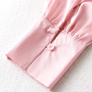 Detailed macro view of pink silk sleeve cuff featuring elegant pleats and button closure