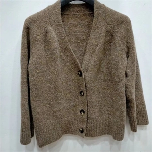 Vue détaillée d'un gilet en tricot marron à col en V avec boutons foncés et bords-côtes