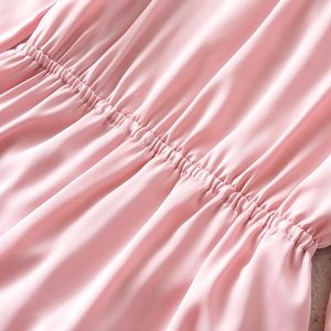 Detailed view of elastic pleated waist and fine sewing on pink satin dress fabric