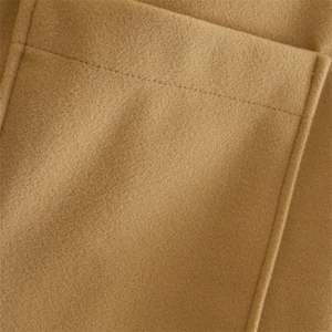 Close-up of camel wool-blend coat featuring a large patch pocket and detailed stitching