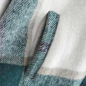 Macro detail of plaid wool shirt jacket showing plush fabric texture and side pocket