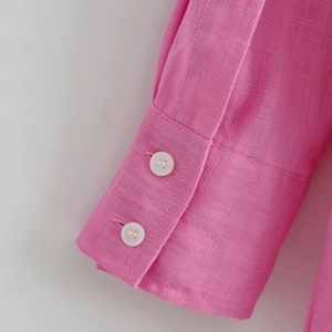 Detailansicht der pinkfarbenen Hemdmanschette mit weißen Knöpfen und Leinenstruktur