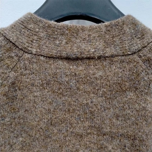 Détail du col en V et de la couture de l'épaule raglan sur le cardigan en maille grise