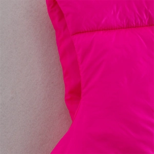 Close-up of vibrant pink puffer vest showing detailed stitching and glossy nylon fabric