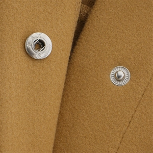 Detailed macro view of metal snap buttons on a camel oversized wool texture shirt jacket