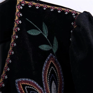 Vista macro detallada de bordados étnicos coloridos en tela de chaqueta de terciopelo negro