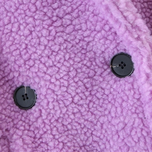 Close-up of soft purple faux fur coat featuring elegant black button detailing
