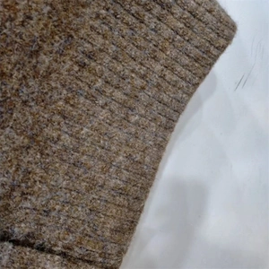 Gros plan sur la maille côtelée épaisse d'un pull marron foncé aux fibres laineuses
