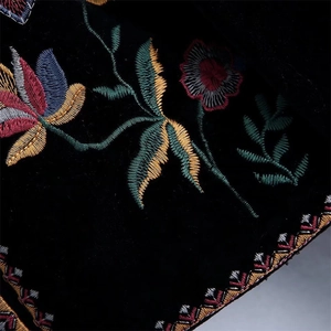 Primer plano de bordado floral colorido sobre textura de tela de terciopelo negro