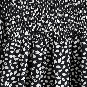 Smocked bodice detail of a black and white leaf print maxi dress with long flared sleeves