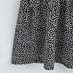 Detailed macro view of black fabric featuring a delicate white leaf and polka dot pattern