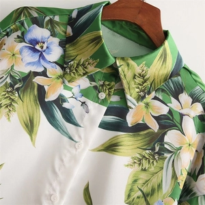 Detail of tropical floral print on a white lapel blouse with white buttons and silky texture