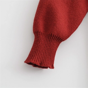 Detailaufnahme des roten Strickärmelbündchens mit klassischer elastischer Rippstruktur