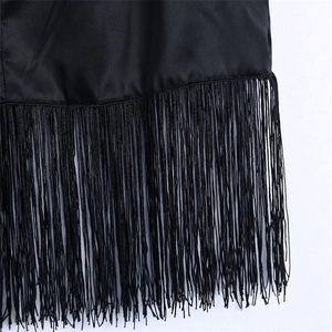 Détail de l'ourlet de la jupe en satin noir avec de longues franges et texture soie