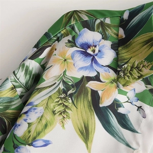 Detailed close-up of tropical floral print fabric with smooth satin texture and small button