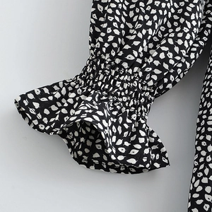 Women's black dress with white leaf print featuring elastic ruffle cuffs and flared sleeves